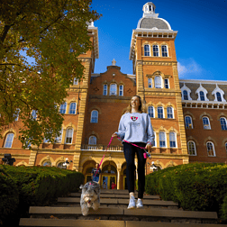 Old Main with female and dog walking through campus